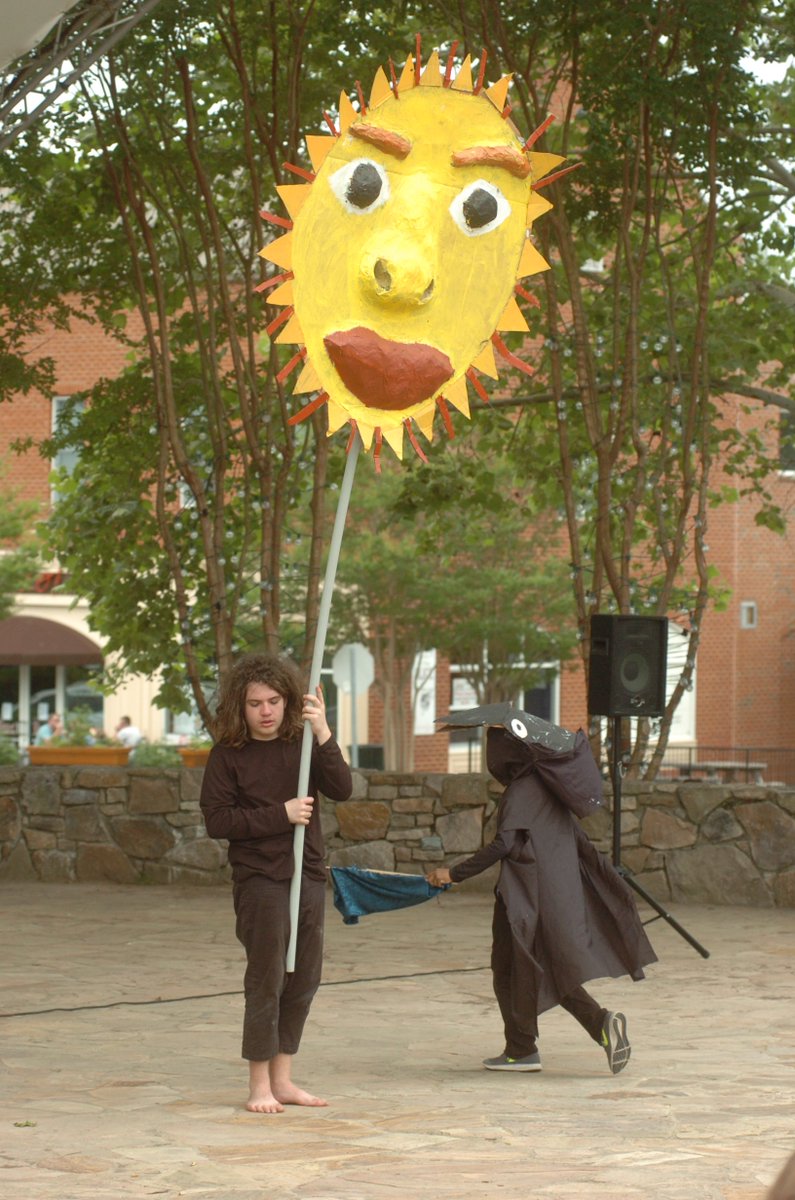 Sol Ramirez puppetiering a large sun puppet with puppeteer Tarin pipkins in a crow mask flying around 