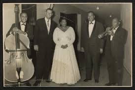 Photograph of bassist Bill Yancey (probable identification), pianist Paul Smith, Ella Fitzgerald, drummer Gus Johnson, and Roy Eldridge.