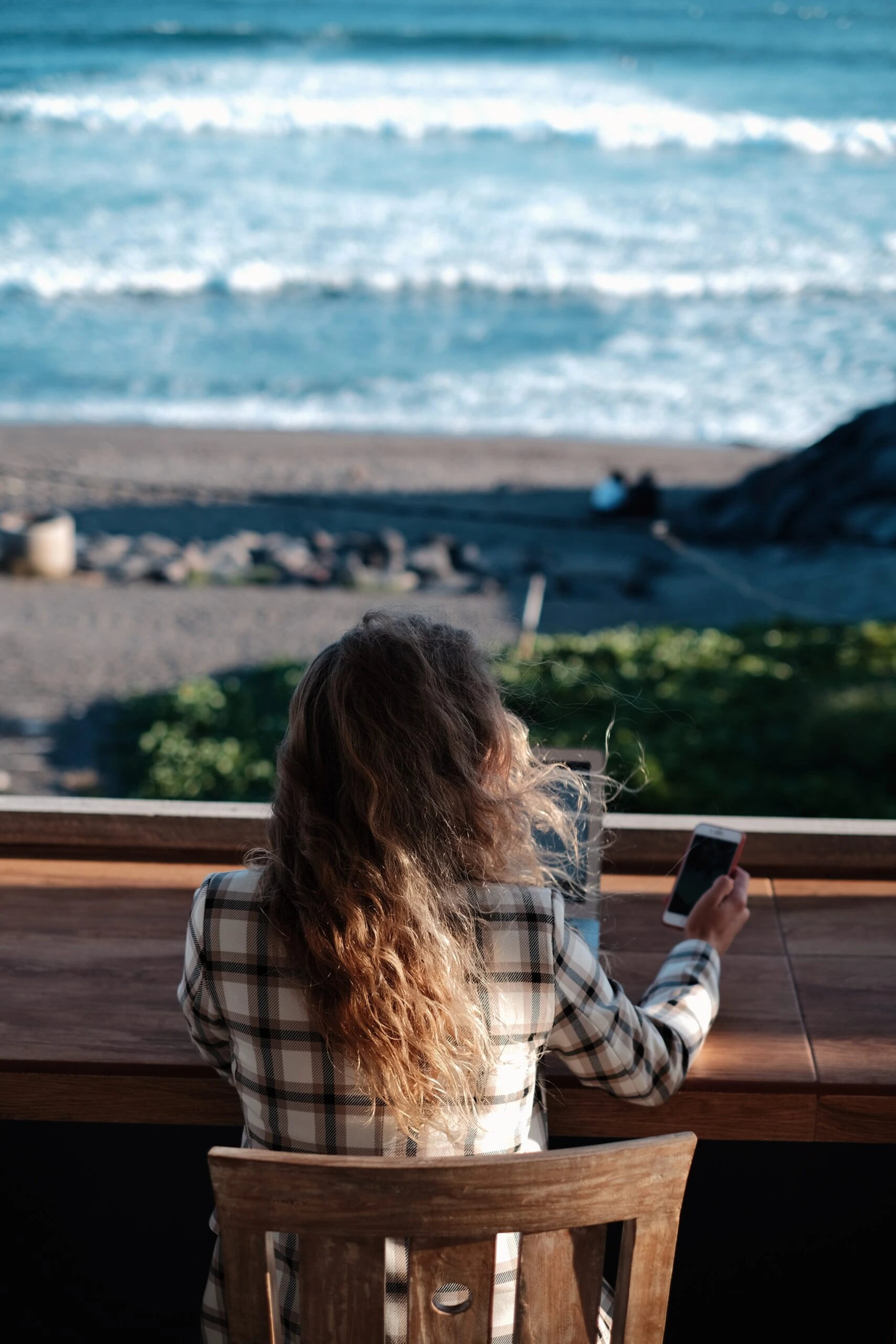 daria-mamont-woman working on laptop on back deck overlooking ocean-unsplash