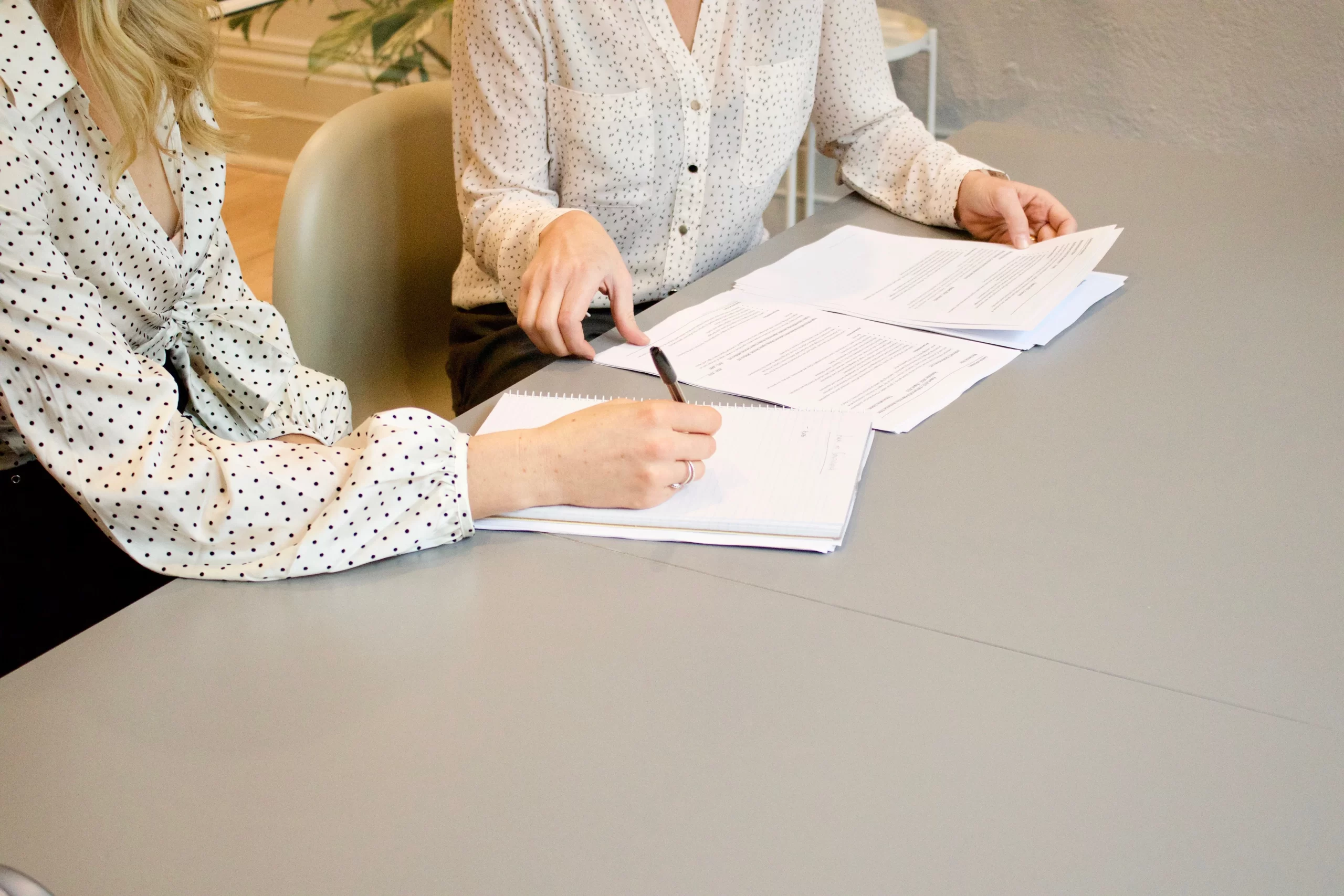 gabrielle-henderson-two individuals signing legal contract at board room table-unsplash