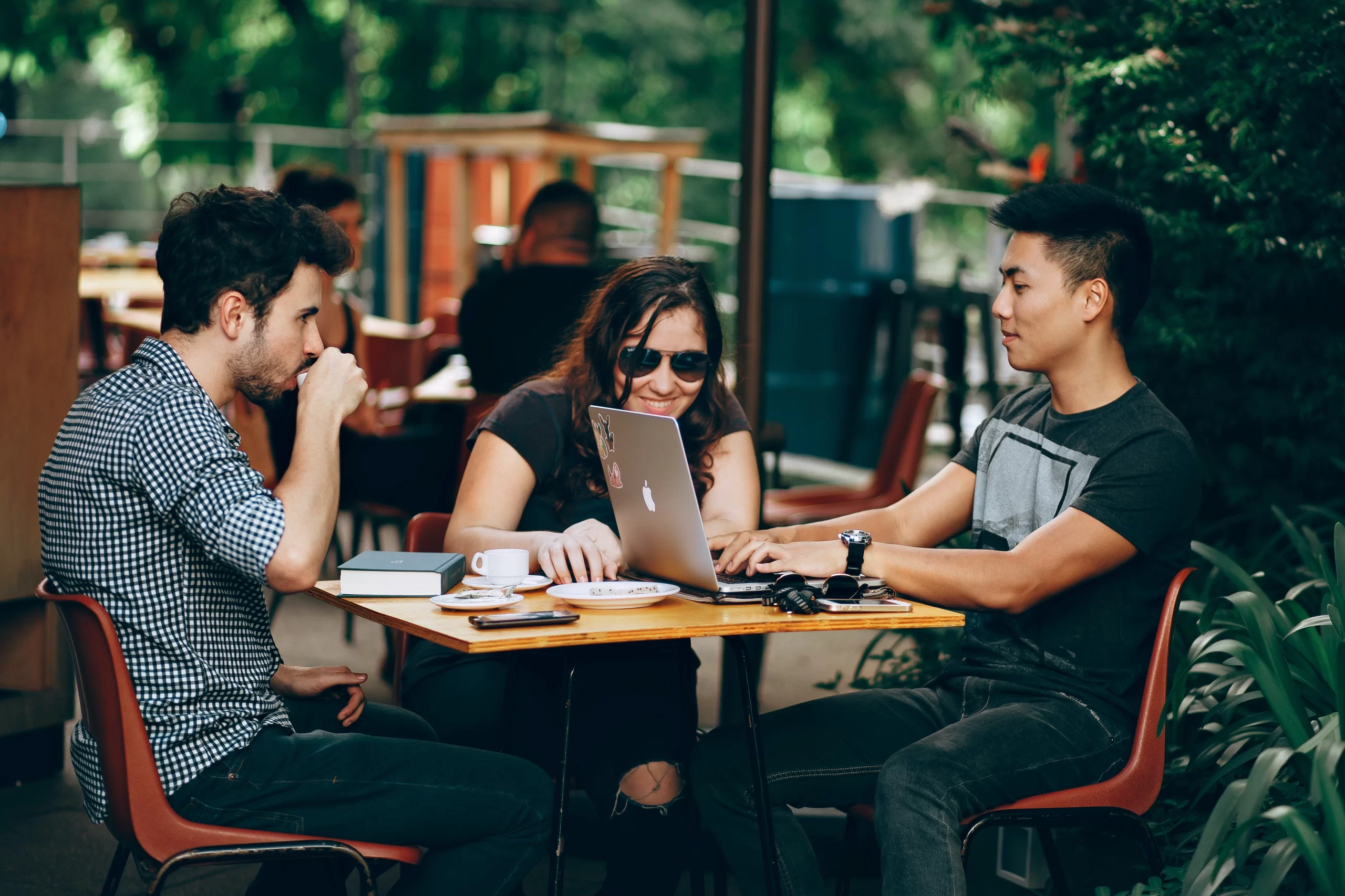 helena-lopes-3 friends (students) around cafe table studying working-unsplash
